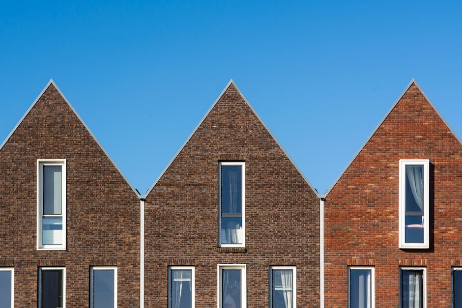 Contemporary brick houses with triangular roofs stand tall under a vivid blue sky.