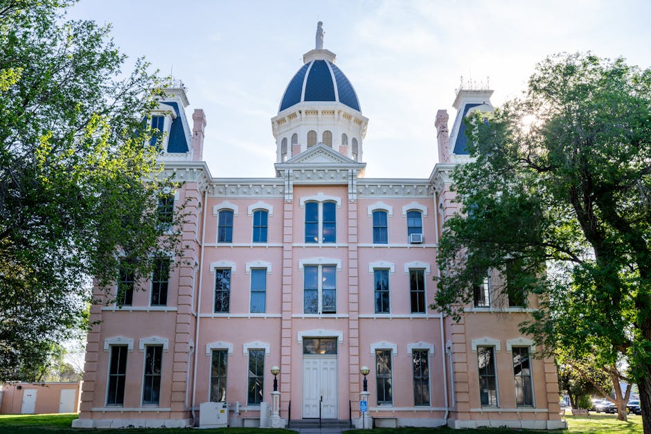Front view of the iconic Presidio County Courthouse in Marfa, Texas, framed by trees under a clear sky.