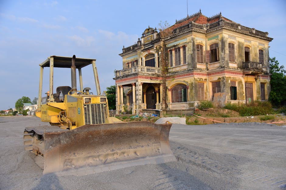 Historic building with a bulldozer outside on a construction site, under a clear sky.