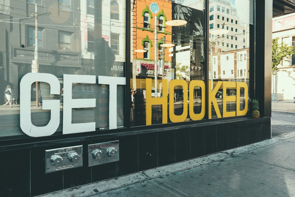 Street scene with a reflection on a glass storefront displaying a 'Get Hooked' sign.